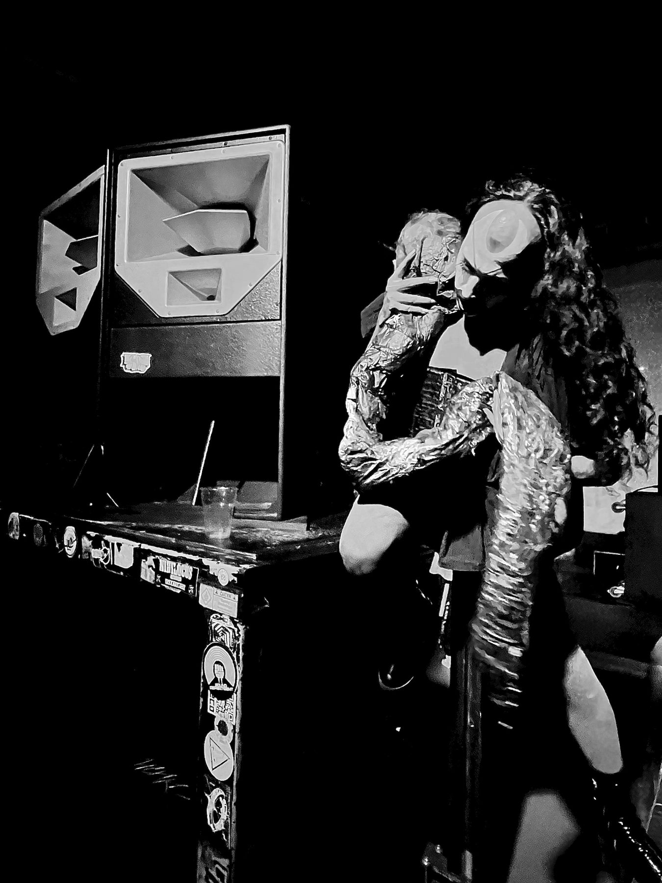 wiqi performing beside a speaker stack, black and white